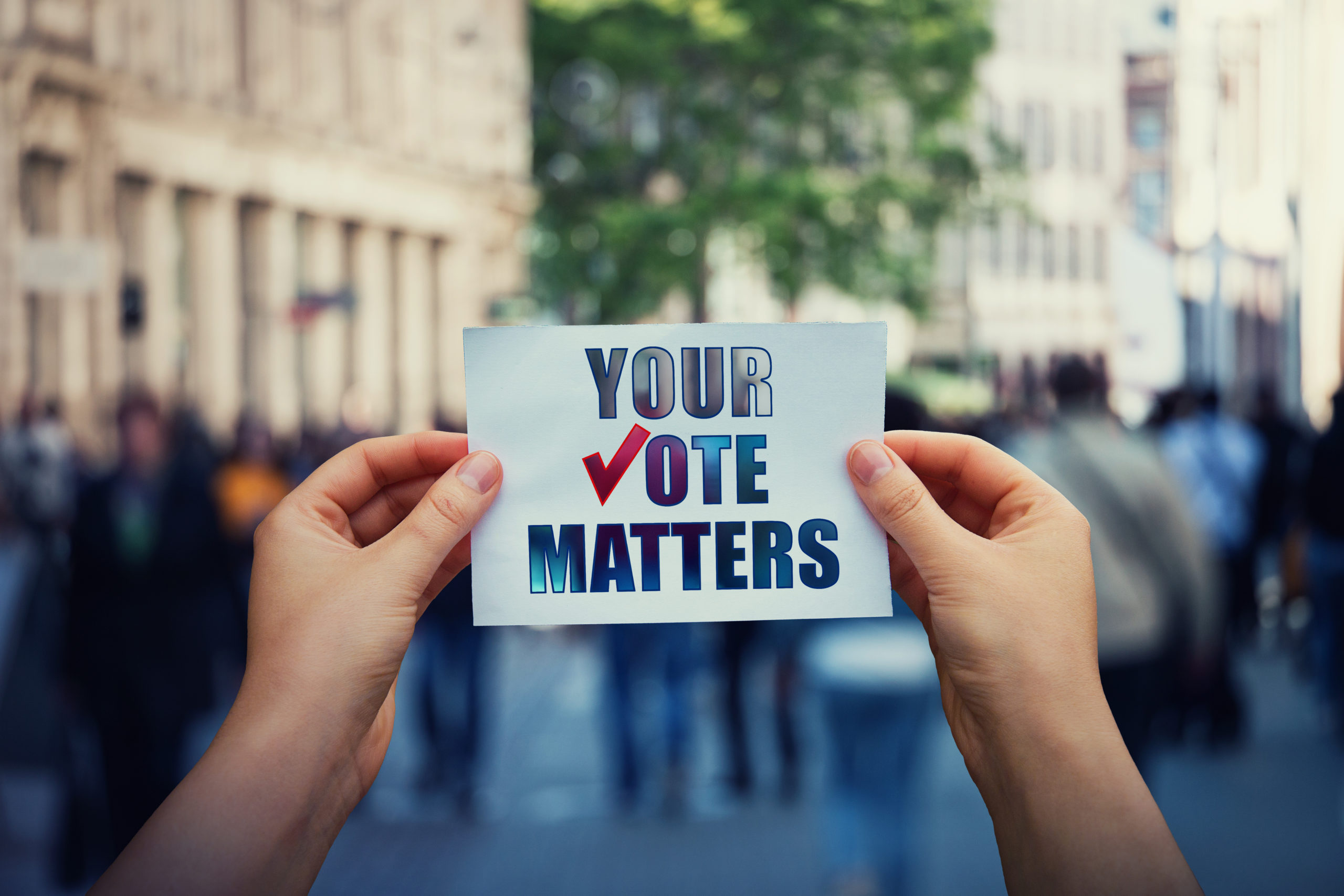 Hands hold a paper sheet with the message your vote matters over